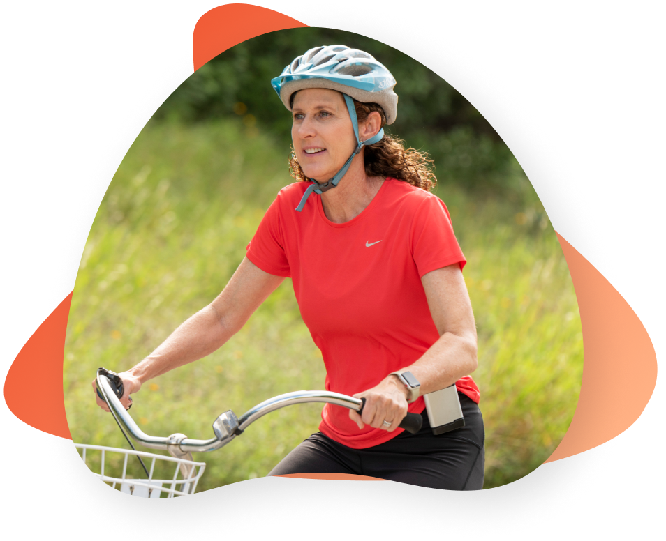 Middle aged woman wearing the ActaStim-S bone growth stimulator rides a bike after her spine fusion.