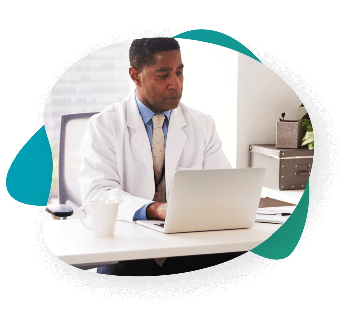 Spine surgeon in a clinic sitting at his desk to review an ActaStim report on his laptop